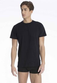 Sort bomulds crew neck t-shirt, korte ærmer, afslappet pasform, glat tekstur, båret med sorte shorts, der viser et simpelt, klassisk design.