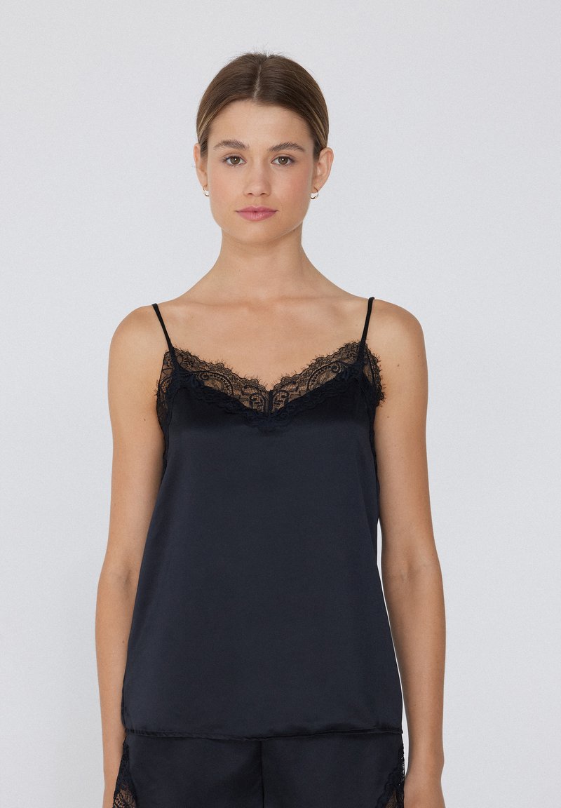 Camisole en satin noir avec bordure en dentelle le long de l'encolure et des bretelles. Dispose de bretelles spaghetti réglables et d'un ourlet droit.
