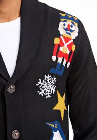 Cardigan nero con chiusura a bottoni, caratterizzato da colorati motivi lavorati a maglia di un soldatino, fiocco di neve, stella e pinguino sul lato anteriore.
