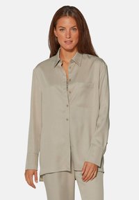Beige Hemd mit Knöpfen aus glattem Stoff, ausgestattet mit einer Brusttasche, langen Ärmeln und einer lockeren Passform mit abgerundetem Saum.