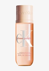 Brume parfumée pour les cheveux et le corps CK Sheer Peach dans un flacon transparent pêche, avec un capuchon métallique et une inscription argentée et rouge bien visible.