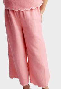 Culottes en lin rose avec un ourlet festonné, texture légère et design à jambe large, idéaux pour un usage décontracté.