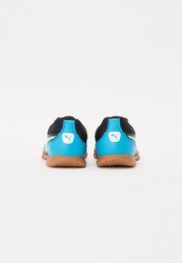 Zapatillas deportivas negras y azules con parte superior de malla, suela de goma texturizada y logo de Puma en el talón y el costado. Presenta un diseño de perfil bajo.