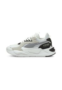 Zapatillas con parte superior de malla blanca y ante, adornadas con acentos en negro y gris. Suela blanca gruesa con detalles texturizados y marca visible en los laterales.