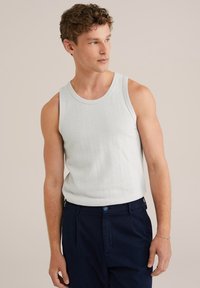 Lichtgrijs, geweven tanktop met een ronde halslijn, gedragen met donkerblauwe broeken. Eenvoudig ontwerp zonder zichtbare patronen of accenten.