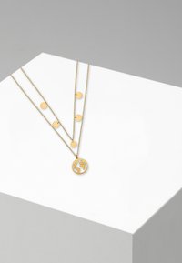Gouden laagjesketting met drie kettingen met cirkelvormige bedels en een hanger in de vorm van een wereldbol. Gladde textuur, minimalistische stijl.