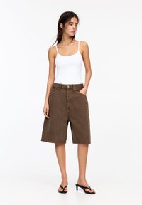 Bruine denim shorts met een hoge taille, zijzakken en een knoopsluiting. De stof heeft een fijne textuur en een rechte snit.