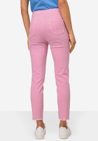 Roze en witte gestreepte jeans met een slim fit, met achterzakken en een rafelige zoom. Draagt samen met witte sneakers.