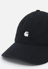 Black cotton baseball cap with a curved brim, featuring a small white logo on the front, soft texture, and six ventilation eyelets.