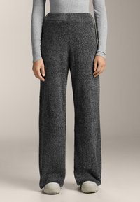 Široké nohavice vyrobené z textúrovaného, tmavošedého pleteného materiálu s vysokým pásom. Majú uvoľnený strih a hladký pás.