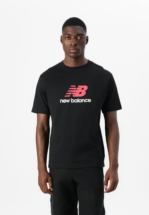 T-shirt en coton noir avec un logo "New Balance" rouge et blanc audacieux. Manches courtes et design classique à col rond.