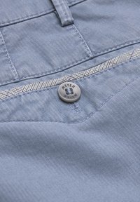 Light blue fabric with fine vertical stripes, featuring a gray button embossed with "MEYER." Includes stitching details and patterned waistband.