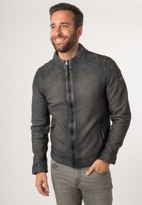 Giacca di pelle nera con colletto alto, zip frontale e tasche laterali. Presenta una finitura testurizzata e cuciture a contrasto.