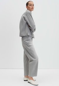 Gray denim jacket and pants with loose fit, paired with white flats. The outfit features minimal detailing and a smooth texture.