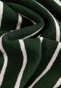 Roheline ja valge triibuline kangas, pehme tekstuuriga, veidi karvane välimus, näidates lainelisi voldikesi ja kõverusi.