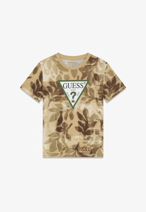 Beżowo-brązowa koszulka z krótkim rękawem w liściasty wzór, z trójkątnym logo Guess z zieloną obwódką i znakiem zapytania na środku przodu.