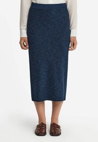 Stickad blå midi kjol med ett strukturerat mönster, med en figurnära midja och rak silhuett, ihop med bruna sandaler med remmar.