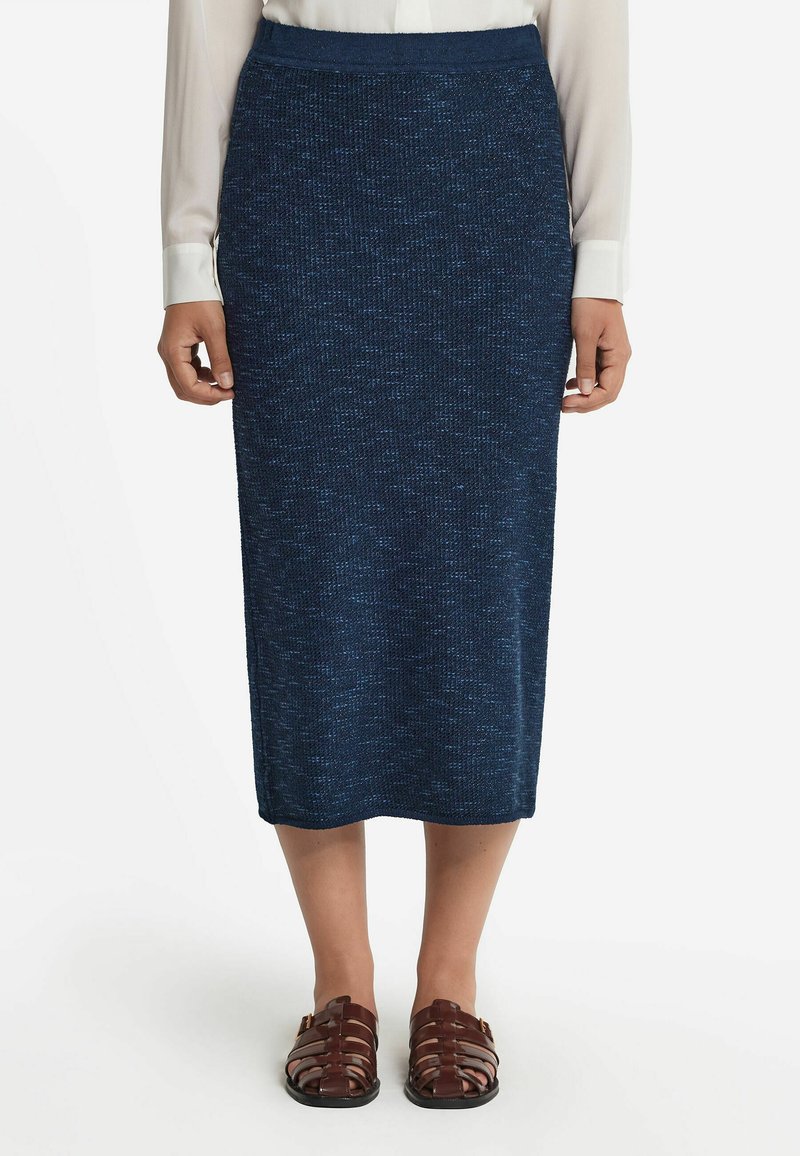 Stickad blå midi kjol med ett strukturerat mönster, med en figurnära midja och rak silhuett, ihop med bruna sandaler med remmar.