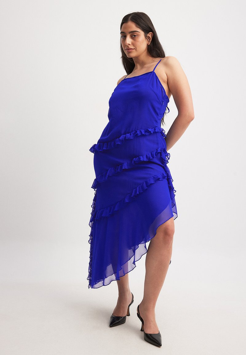 Royal blue dress made of lightweight fabric, featuring ruffled accents along the front, asymmetric hemline, and thin spaghetti straps.