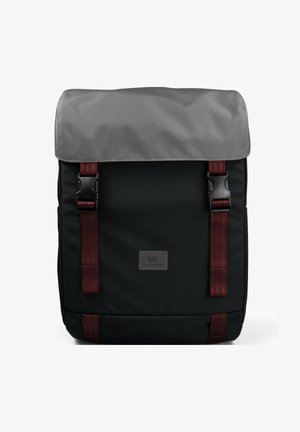 Zaino nero con alette grigie, spallacci bordeaux e hardware nero. Presenta una patch con logo sulla parte anteriore. Realizzato in tessuto resistente.