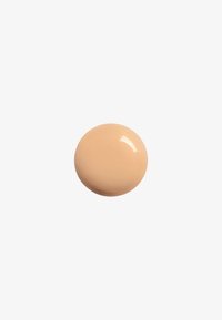 Grosse tache circulaire de crème beige avec une texture lisse et brillante et des bords doux, sur un fond blanc uni.