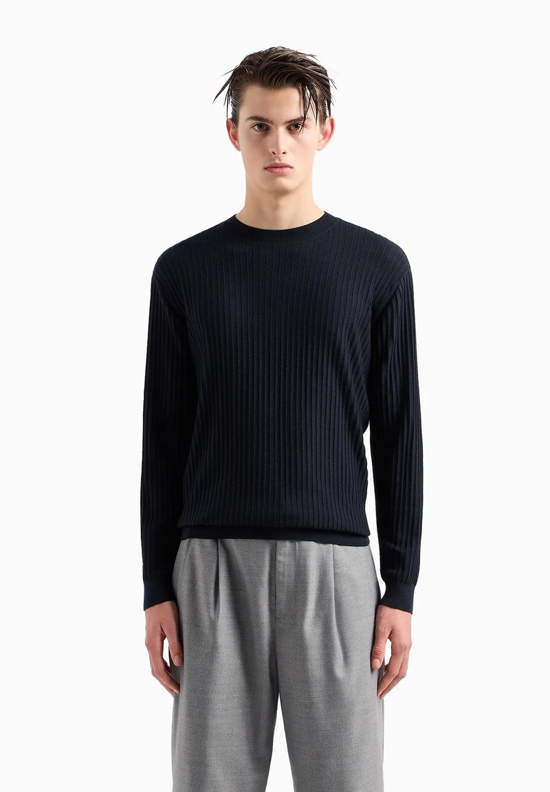 Maglione a coste blu navy con scollo rotondo, maniche lunghe e silhouette aderente, abbinato a pantaloni beige chiaro sartoriali.