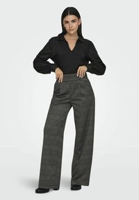 Black long-sleeve blouse with a V-neck and puffed sleeves paired with high-waisted, wide-leg pants featuring a grey plaid pattern.