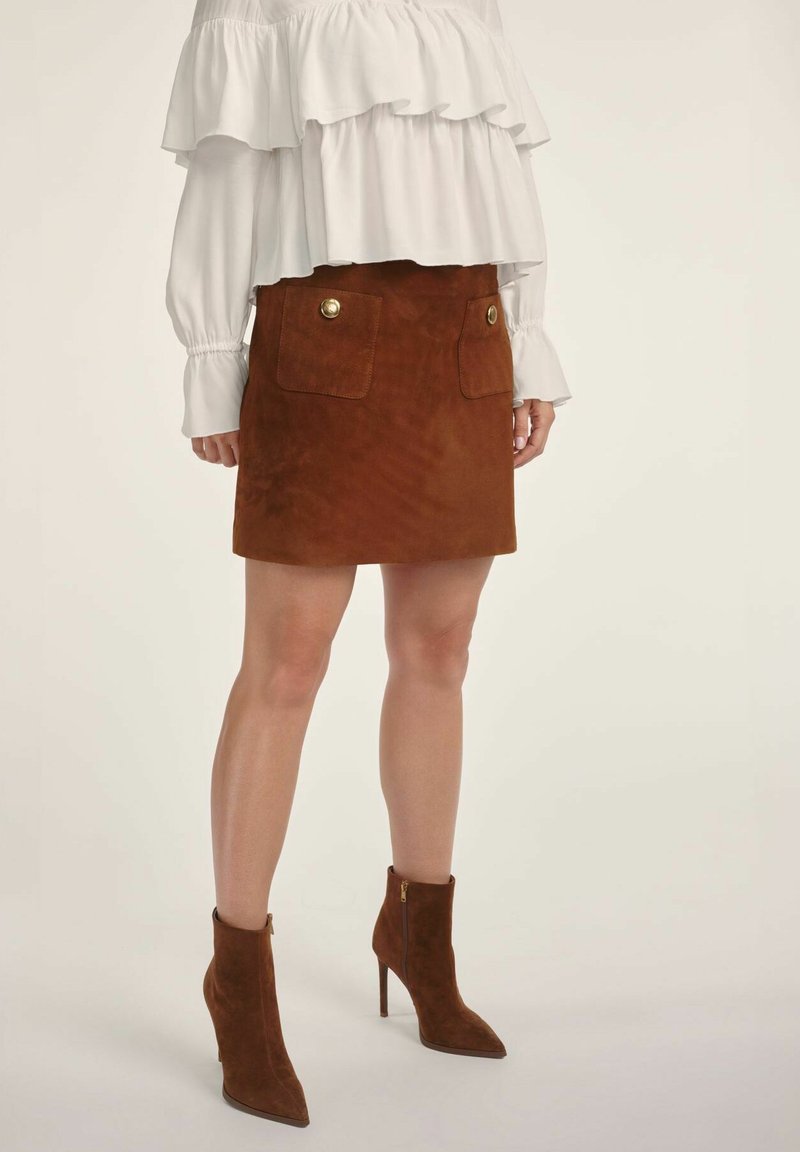 Brąspiana zamszowa mini spódniczka z dwiema przednimi kieszeniami, złotymi guzikami i miękką fakturą, w połączeniu z brązowymi zamszowymi botkami za kostkę.