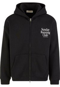 Felpa nera con zip realizzata in materiale per felpe. Presenta una tasca frontale, polsini a coste e la scritta "Sunday Running Club" in bianco.