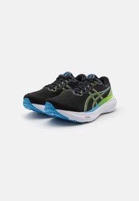 Scarpe da ginnastica nere con accenti verdi e blu, tomaia in rete, design con lacci e suola blu testurizzata per grip e supporto.