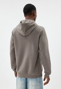 Grijze hoodie gemaakt van een katoenmix, met een kangoeroezak, ribgebreide manchetten en zoom, gezien vanaf de achterkant.