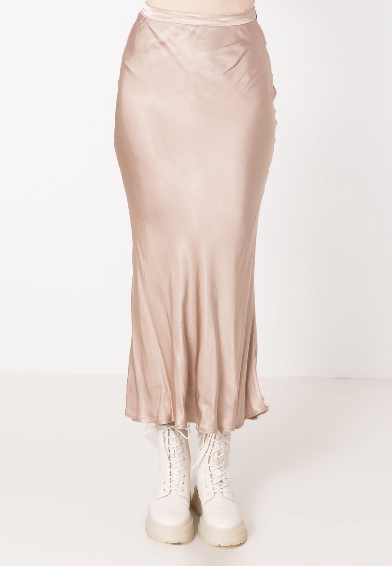 Gonna di raso, rosa chiaro, con una silhouette fluida. Presenta una vita aderente e un leggero svaso all'orlo. Abbinate a stivali bianchi con lacci.