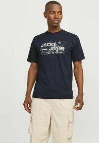 Zilas kokvilnas T-krekls ar izbalējušu "JACK & JONES" printu baltā un pelēkā krāsā. Īsas piedurknes, apaļa izgriezuma kakla daļa, brīvs griezums.