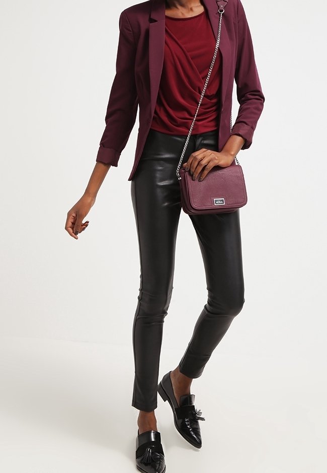 Burgunder blazer over en draperet burgunder top, parret med skinnende sorte faux læderbukser og sorte loafers med sløjfe-detaljer. Crossbody-taske medfølger.