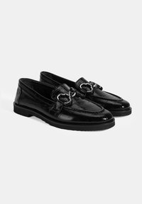 Zwarte loafers vervaardigd uit glanzend krokodillenpatroonmateriaal, met een decoratieve zilveren hardware-detail in de vorm van een hartje aan de voorkant.