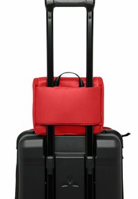 Zwarte koffer met een gestructureerd oppervlak en een uitschuifbare handvat, bovenop een rode zachte handbagage met dubbele handvatten en een rits.