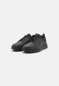 Zapatillas deportivas negras con parte superior de cuero texturizado, puntera redonda y suela de goma plana. Presentan un sistema de cordones tradicional y una lengüeta en el talón.