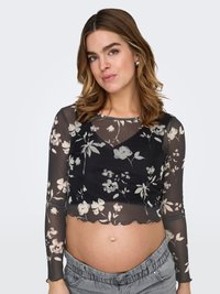 Läpinäkyvä musta paita kukkakuvioinnilla, pitkät hihat ja aaltoileva helmaviiste. Yhdistetty vaaleanharmaisiin, joustavavyötäröisiin housuihin.