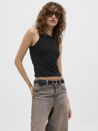 Top aderente nero abbinato a jeans a gamba larga color marrone chiaro a vita alta, con una cintura nera. La modella ha i capelli ricci e occhiali da sole alla moda.