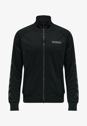 Black zip-up jacket made of smooth fabric, featuring a high collar, raglan sleeves, and grey chevron accents on the arms. "HUMMEL" logo on chest.