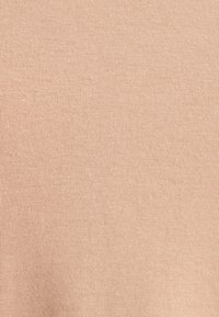 Tissu beige clair avec une texture douce et lisse et un motif à fines côtes, présentant une coloration uniforme.