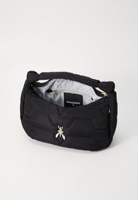 Borsa a tracolla nera in nylon trapuntato con un'unica fantasia esagonale, accessori in argento, un emblema decorativo di un insetto e fodera interna grigio chiaro.