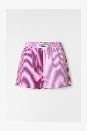 Stripete shorts i rosa og lilla nyanser, med elastisk midjebånd og en etikett med teksten "COLOURFULL REBEL." Lett stoff.