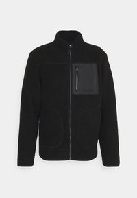 Veste polaire noire avec une fermeture éclair à l'avant, un col montant et une poche poitrine. Caractérisée par une texture douce, un ourlet arrondi et deux poches latérales.