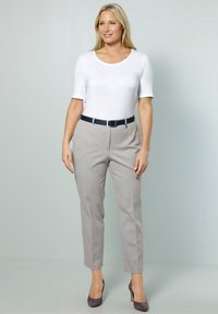 Pantaloni grigi chiari su misura con una texture liscia, dotati di una vestibilità slim e una cintura blu scuro. Abbinati a un top bianco aderente a maniche corte.