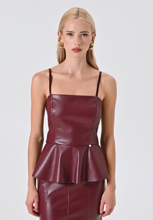 Top peplum in finta pelle bordeaux con spalline sottili, caratterizzato da un busto aderente e una leggera lucentezza. Dettaglio semplice in argento in vita.
