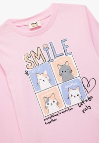 Roze katoenen sweatshirt met een vierkante afbeelding van vier cartoonkatten, de tekst "SMILE" en zinnen als "have fun" en "let's go play."