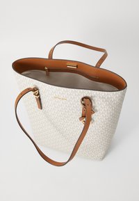 Sac fourre-tout en toile imprimée et cuir marron. Présente des poignées doubles, une ouverture sur le dessus, une poche intérieure zippée et des accents en métal doré.