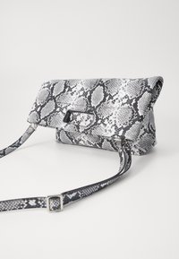 Snake-patterned handbag in black and white, with a flap closure and a detachable strap. Features a smooth, textured surface and silver hardware.