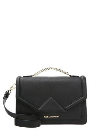Schwarze Karl Lagerfeld Lederhandtasche mit goldenem Logo, Ketten-Obergriff und angebrachtem verstellbaren Schulterriemen auf weißem Hintergrund.